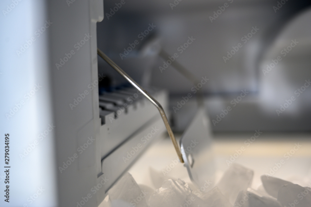Inside a freezer automatic ice maker with pile of cubes Inside a freezer automatic ice maker with pile of cubes