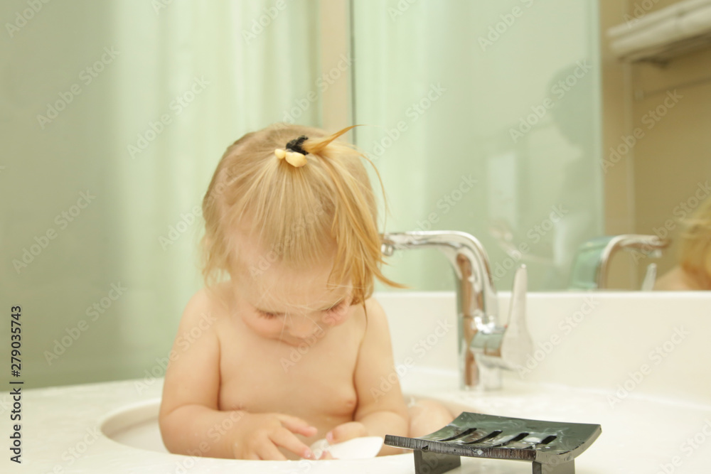 Cute blonde baby taking bath in bathroom sink Cute blonde baby taking bath in bathroom sink