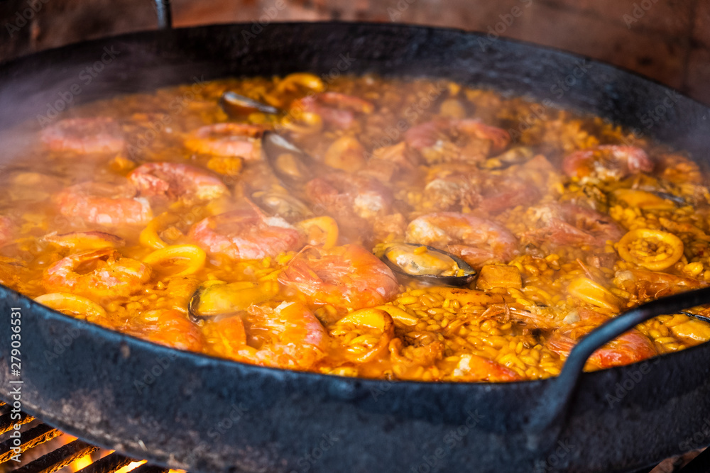 Cooking and making a traditional Spanish paella over open fire with