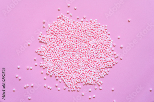 Pile of pink plastic resin granules. Rose granular texture background. Sweetener tablets on rose powder background.