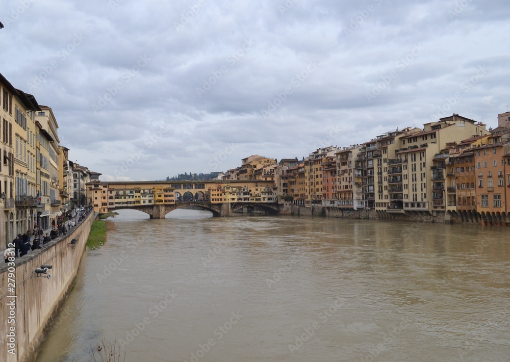 Fototapeta premium View of the Ponte Vecco bridge, ancient buildings and the Arno River in Florence on an overcast day.