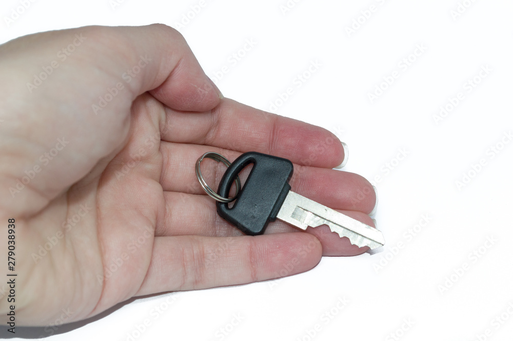 Caucasian female extended hand palm holding a black key; conquest, own house, own car concept