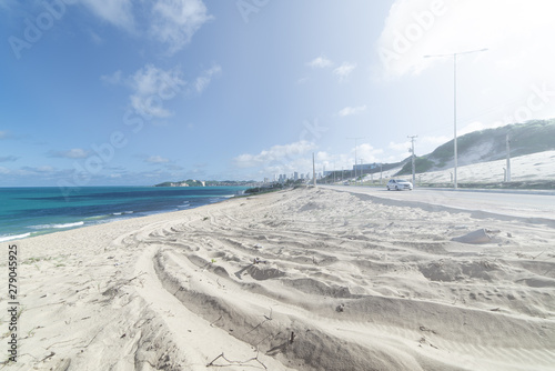 Sand dune leading to a road that ends at the beach. clear sky. Natal, Rio Grande do Norte, Brazil.