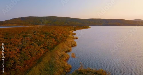 Flying above beautiful lake Blagodatnoye surrounded with green forests and mountains on the background. Sikhote-Alin Nature Reserve in Russia for the endangered Siberian tiger founded in 1935. Aerial photo