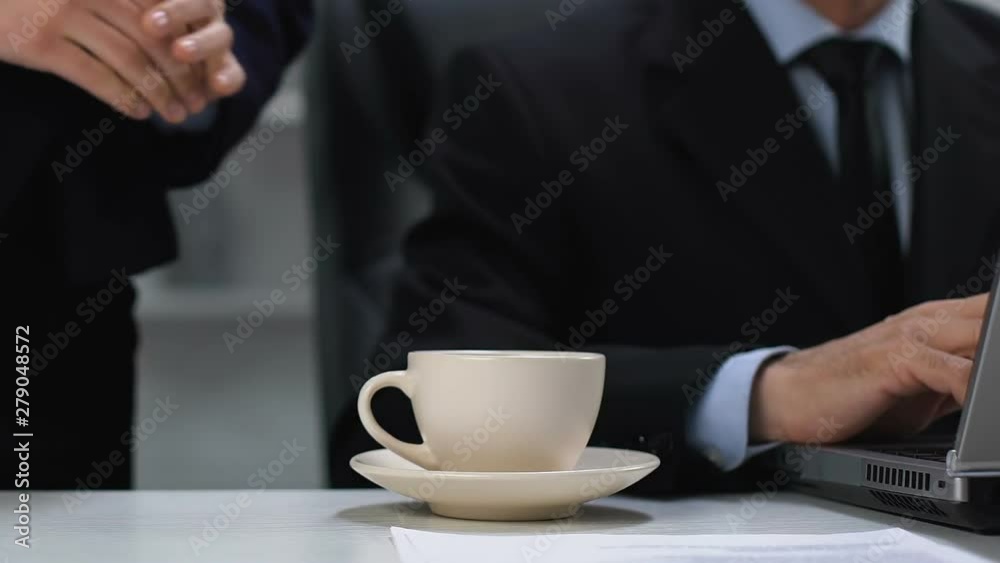 Female secretary serving coffee cup for male director working laptop, assistance Female secretary serving coffee cup for male director working laptop, assistance