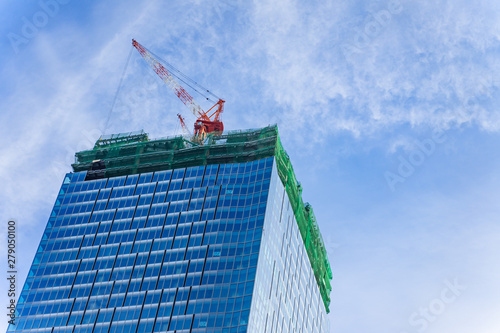 Wallpaper Mural Construction crane on top of tower working to build high skycrapper office building in the development city, cloud blue sky Torontodigital.ca