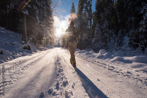 young photographer walking on snowy country road