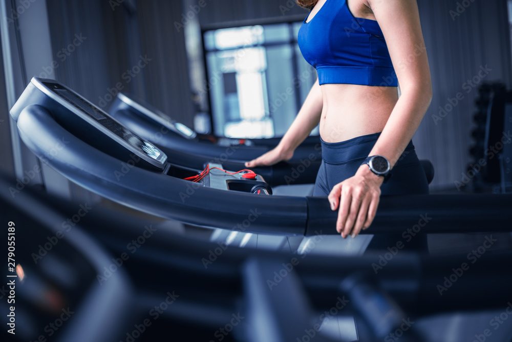 Attractive sportswoman running on treadmill in the gym. Close up