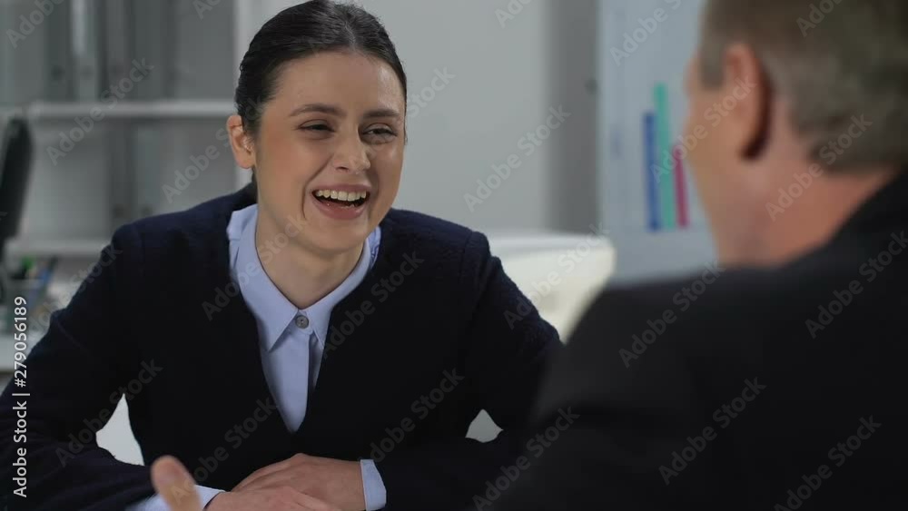 Happy male and female colleagues laughing giving high five, friendly atmosphere Happy male and female colleagues laughing giving high five, friendly atmosphere