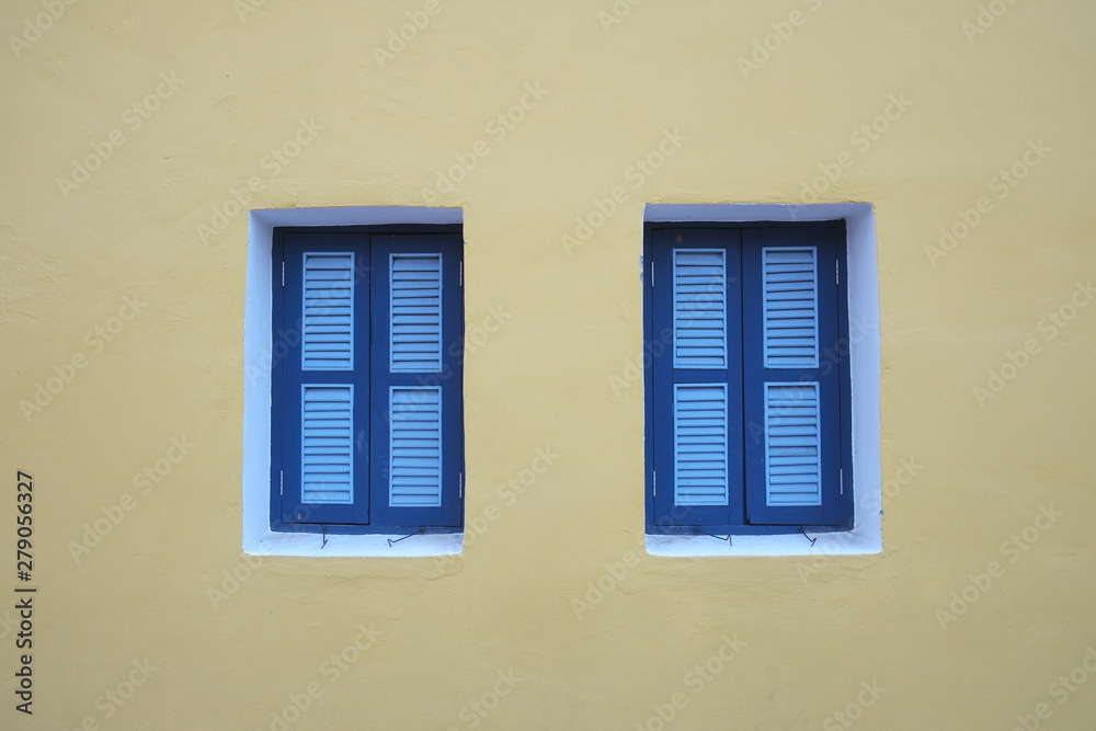 Two blue windows on yellow wall Two blue windows on yellow wall