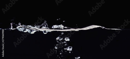 Rippling liquid surface and small water bubbles underwater, isolated on black background, close up view. Abstract black background for overlays design, screen blending mode layer