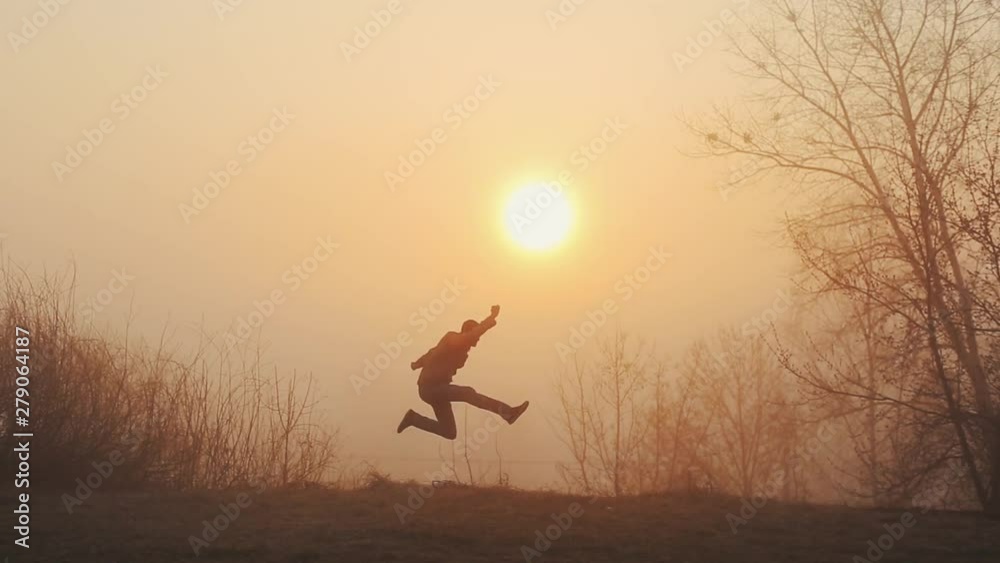 Silhouette of funny crazy man dancing against sunrise or sunset. successful joyful and cheerful man dancing on the background of the sun.