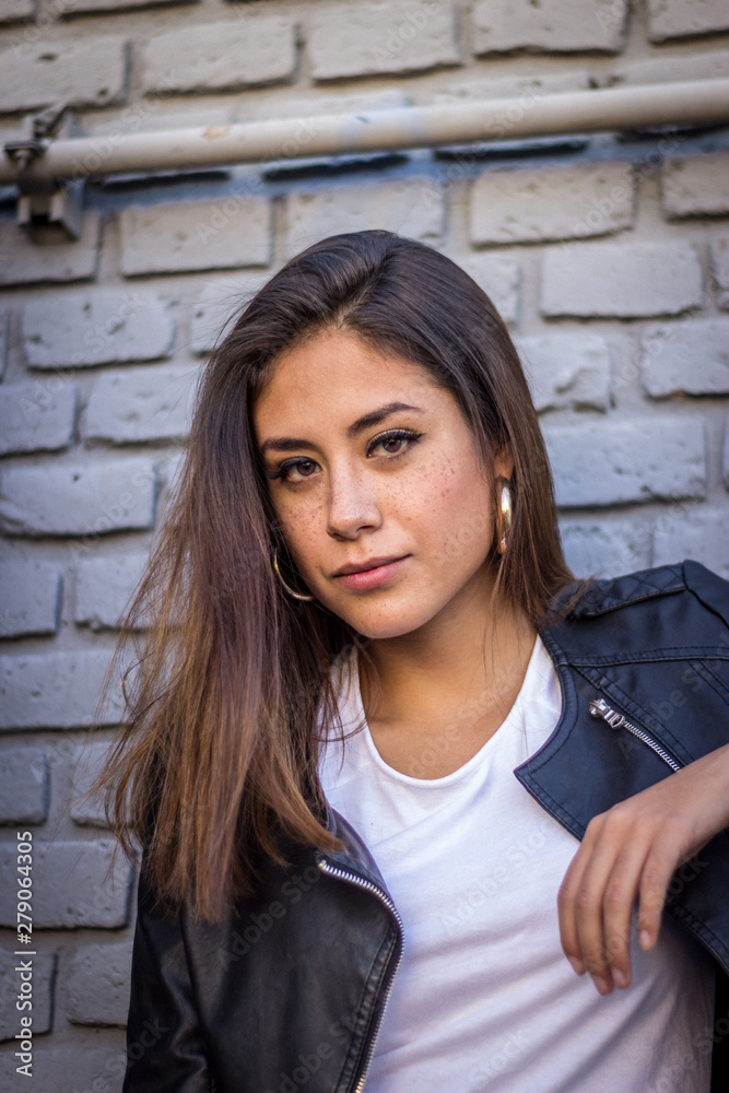 Joven mujer chica en pantalones de mezclilla con actitud en pared de ladrillos y escaleras Joven mujer chica en pantalones de mezclilla con actitud en pared de ladrillos y escaleras