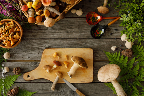 Mushrooms on old wooden background. Card on autumn or summertime. Forest harvest. Boletus, chanterelles, leaves, berries. Flat lay.