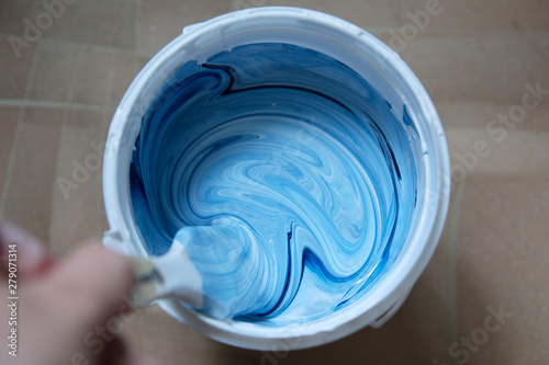 Fotografie Can of white-blue paint (mixing) with a brush, top view.