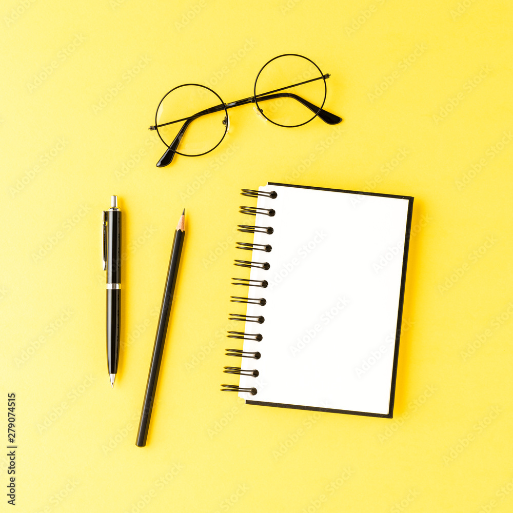 Empty notebook with pens and eyeglasses on yellow table. Office desktop Empty notebook with pens and eyeglasses on yellow table. Office desktop