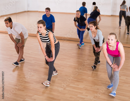 Teenage boys and girls with trainer stretching in dance hall