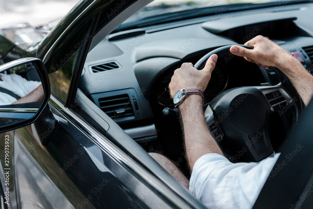 cropped view of man holding steering wheel while driving automobile