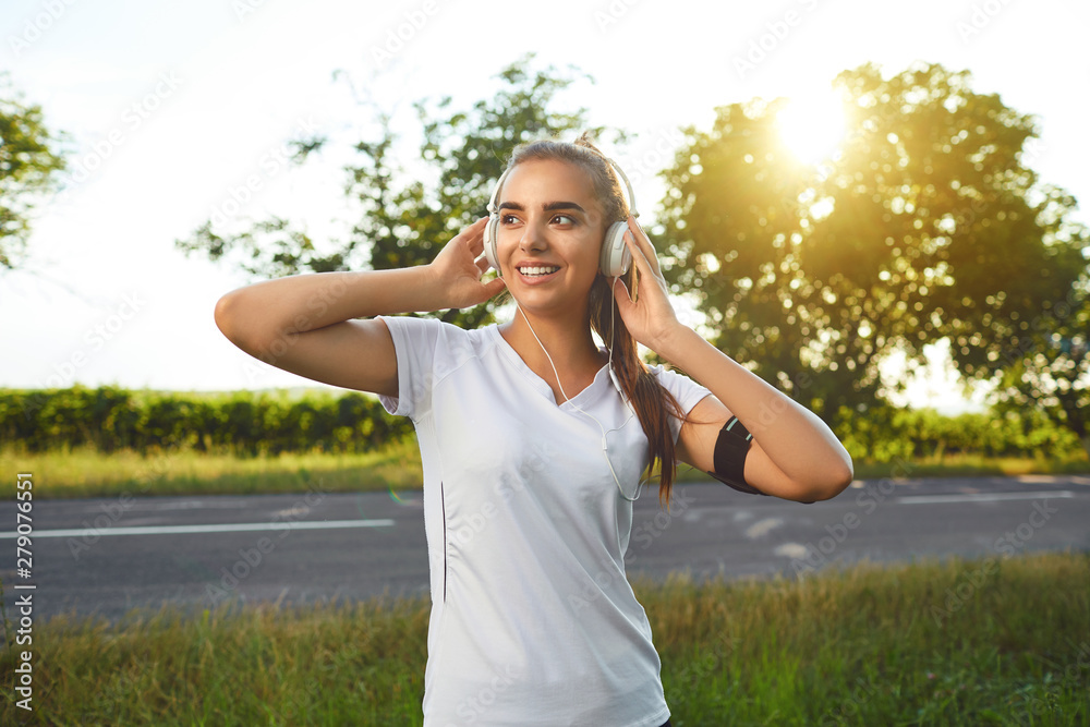 Girl runner with headset resting before jogging on the road Girl runner with headset resting before jogging on the road