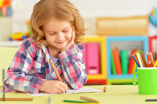 Portrait of cute smiling girl posing and drawing at home