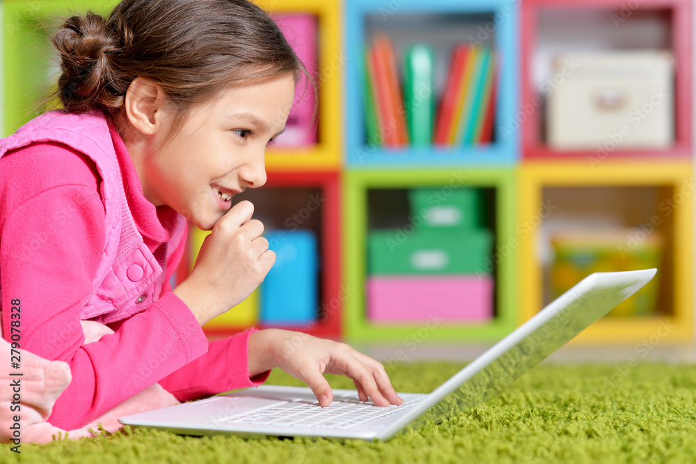 Emotional cute girl using laptop while lying on floor Emotional cute girl using laptop while lying on floor