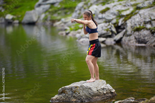 Woman kickbox fighter training by the lake