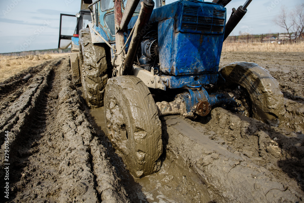 Tractor stuck in the mud on a bad road. Clay stuck on wheels. Stock