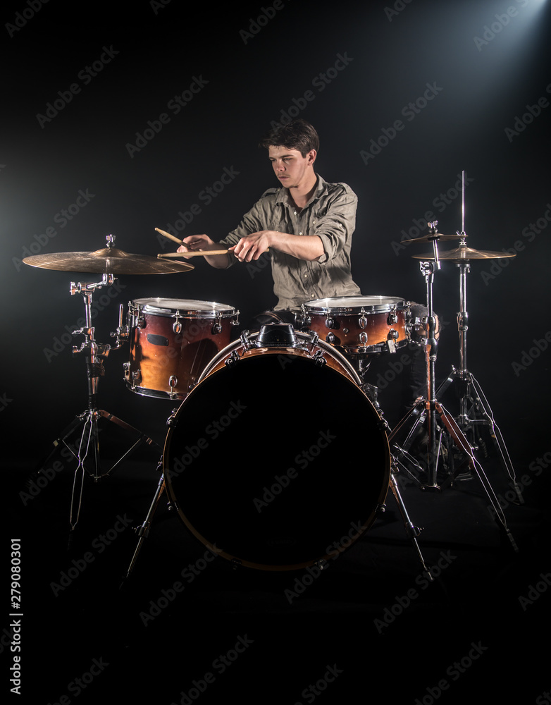 Fototapeta premium Professional drummer playing on drum set on stage on the black background