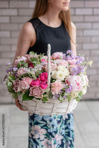 Flower arrangement in Wicker basket. Beautiful bouquet of mixed flowers in woman hand. Floral shop concept . Handsome fresh bouquet. Flowers delivery