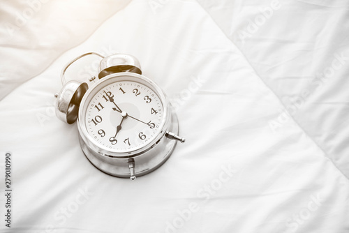 Ringing alarm clock on white bed sheet. Top view of object. 8 o clock setting up