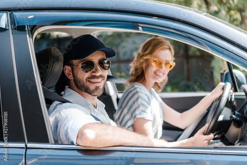 selective focus of happy man in sunglasses smiling near attractive woman driving car © LIGHTFIELD STUDIOS