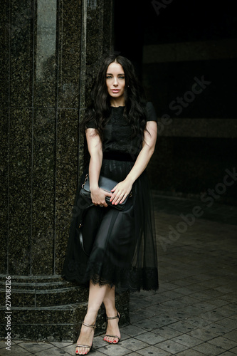 woman in a black dress walks the city