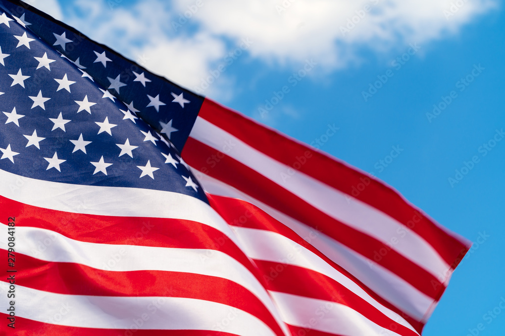Fototapeta premium American flag waving in the wind against blue sky