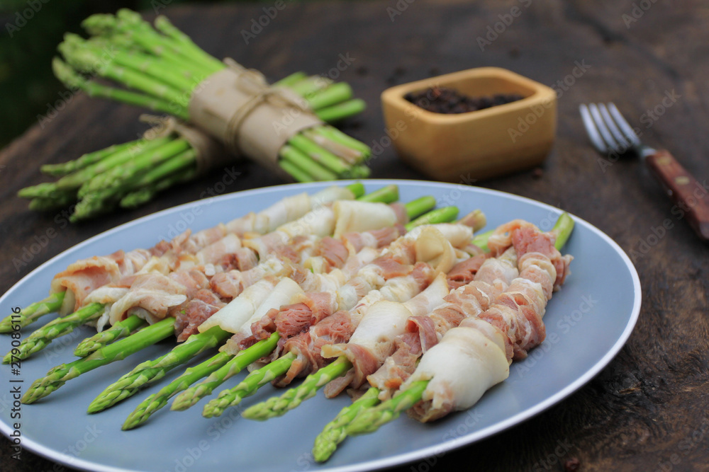 Raw bacon wrapped green asparagus on wooden dark background