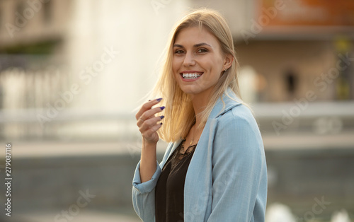 Woman smiling with perfect smile and white teeth in a park and looking at camera.