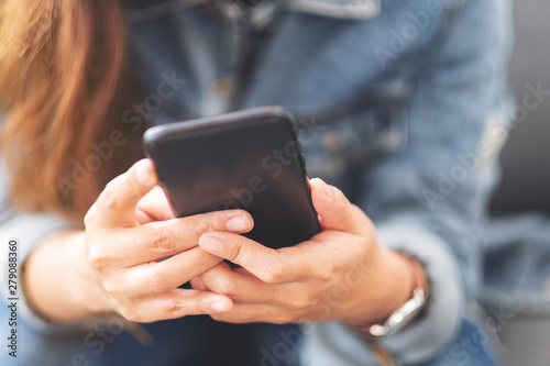 Closeup image of a woman holding , using and looking at smart phone