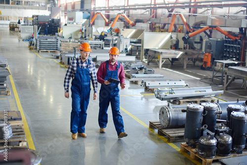 Engineers in hard hats working at the industrial plant.