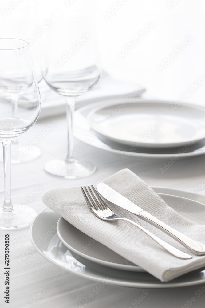 Table setting white and grey colour. Empty glasses and plates set with napkin and cutlery. Restaurant interior background... - obrazy, fototapety, plakaty 
