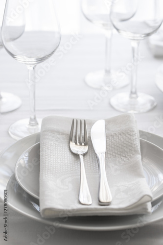 Table setting white and grey colour. Empty glasses and plates set with napkin and cutlery. Restaurant interior background...