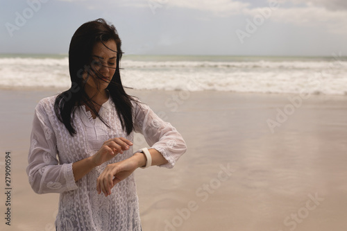 Young woman using smartwatch on beach