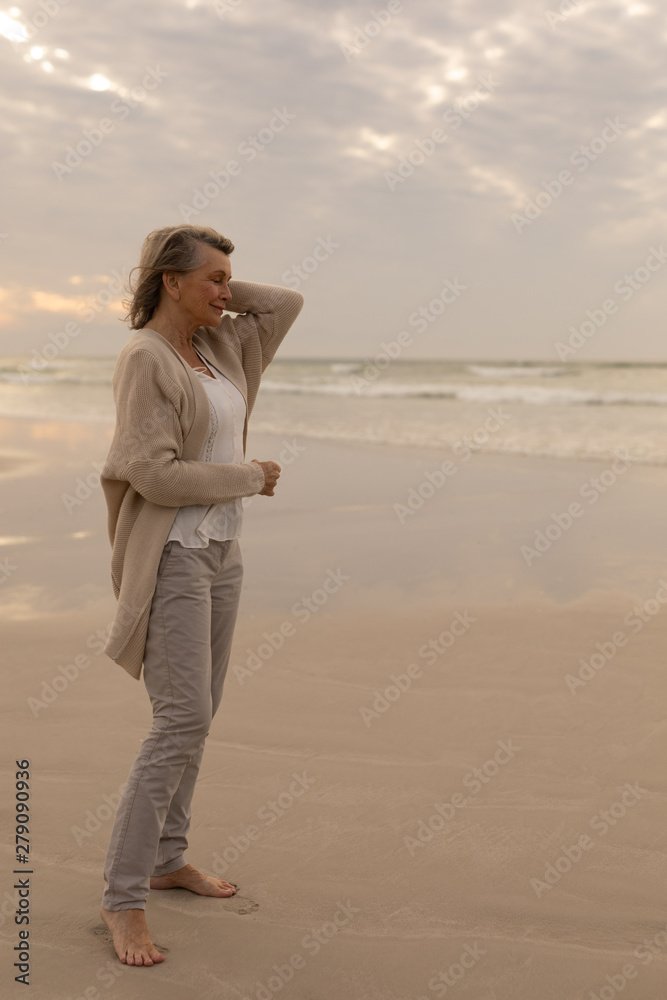 Senior woman standing with eyes closed on the beach