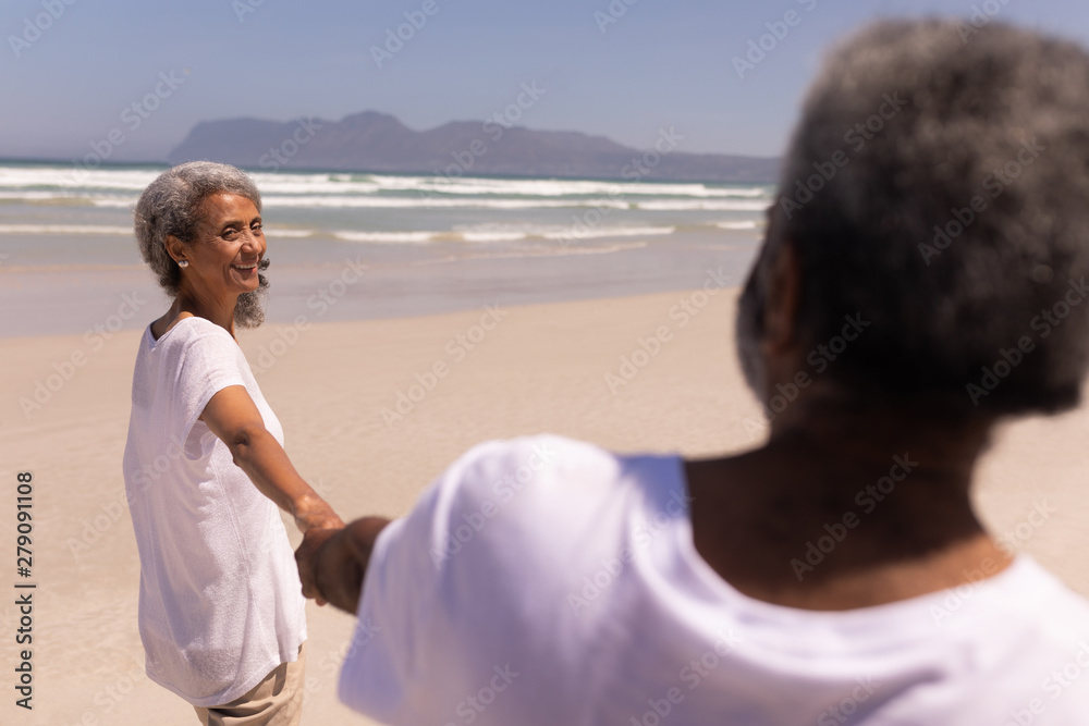 Senior couple holding hands on beach 