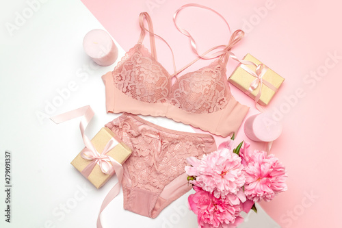 Female lace pink underwear with a pink ribbon and candles on a pink background.