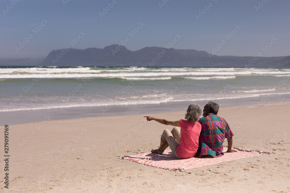 Senior couple sitting on blanket at beach