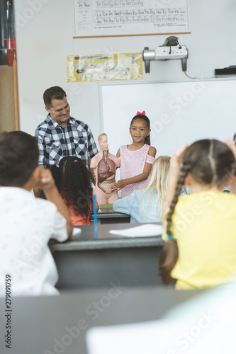 Schoolgirl explaining to his classmates the functioning of body humant thanks to a dummy skeleton  photo