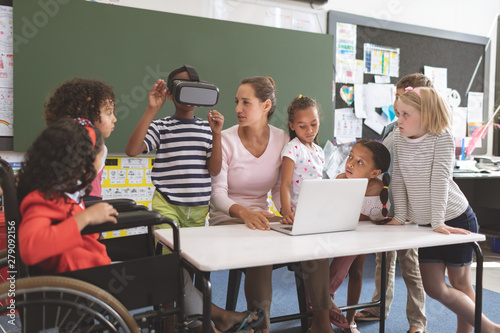 Schoolboy using virtual reality headset at school in classroom photo