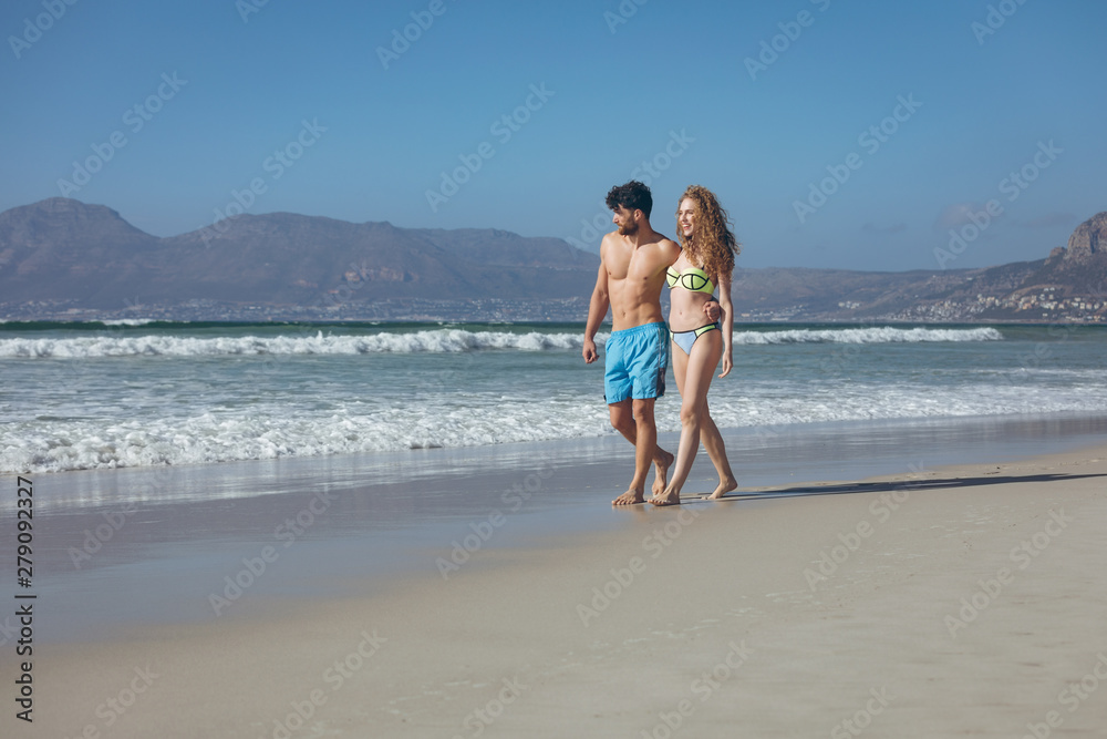 Couple walking with arm around at beach 