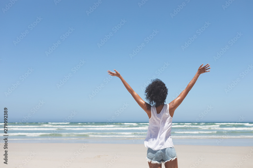 Beautiful woman standing with open arm at beach on sunny day Beautiful woman standing with open arm at beach on sunny day