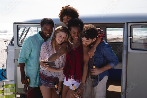 Group of friends taking selfie while having beer at beach 