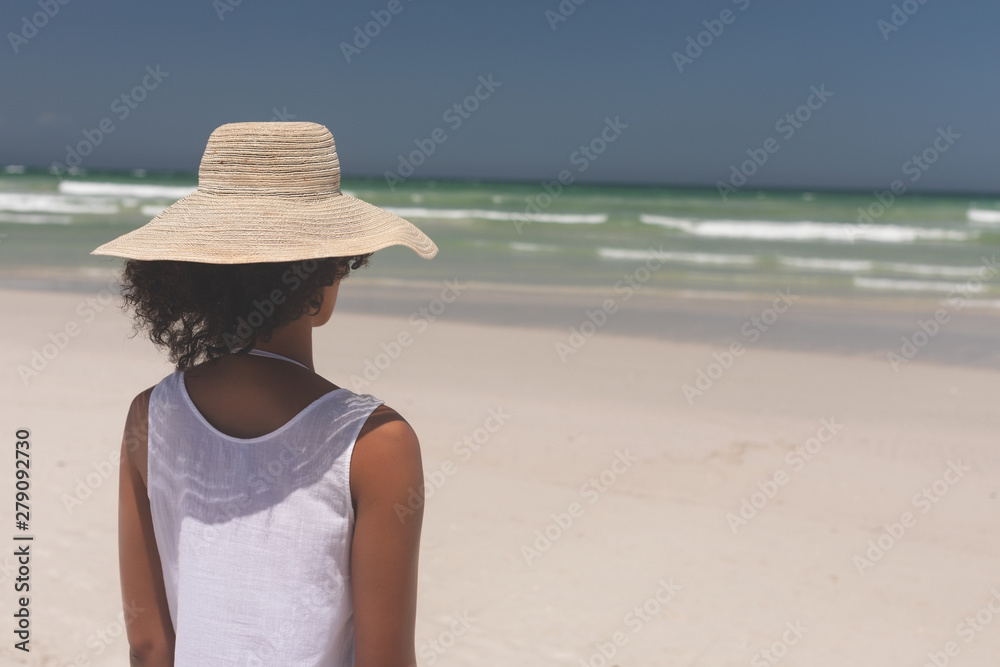 Beautiful woman standing at beach on sunny day